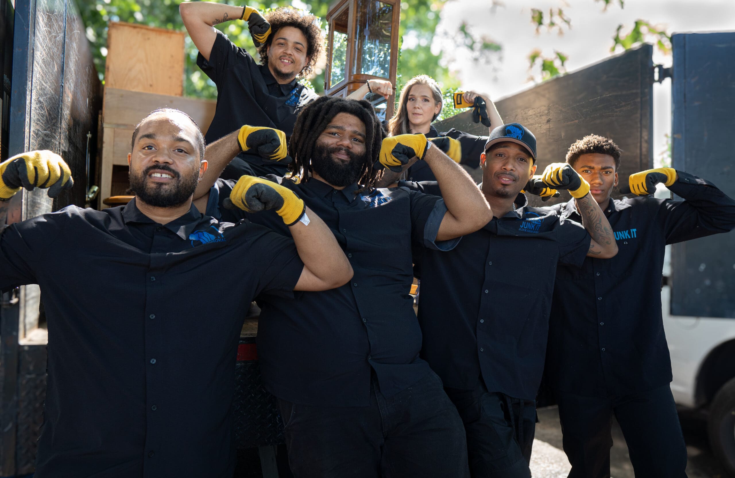 Junk It Portland team of 7 employees doing strong arms in front of our truck